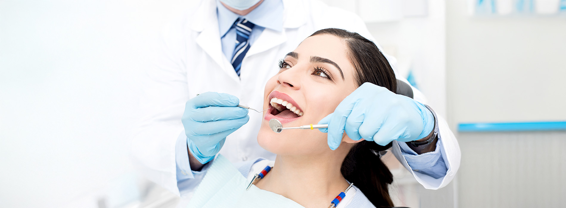 The image shows a dental professional performing a dental procedure on a patient, with both individuals wearing protective gloves and masks.