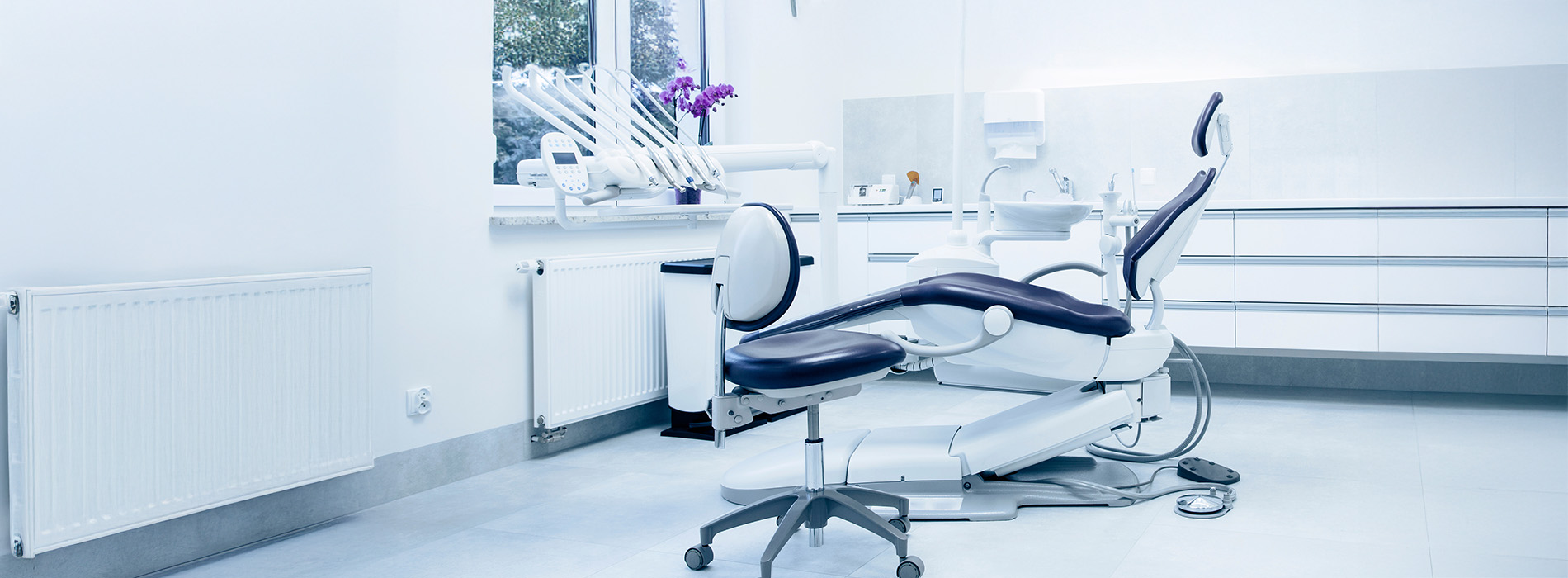 The image shows a modern dental office interior with equipment, chairs, and a sterile environment.