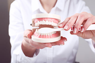 The image shows a person holding a set of dental implants with a smile, likely for educational or promotional purposes related to dental care or implant treatments.