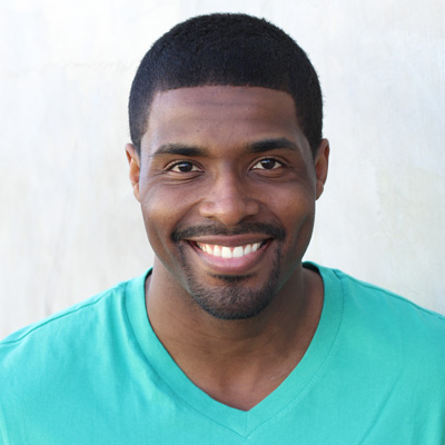The image shows two elderly individuals, an older man and woman, smiling at the camera while sitting closely together.